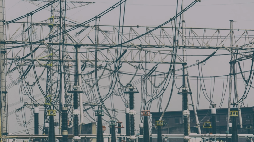 Complex electrical substation with high-voltage power lines, transmission towers, and multiple dark gray insulators, representing robust energy infrastructure.